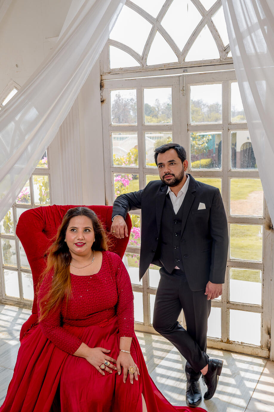 High-fashion editorial modelling shoot featuring a red tail gown against minimalist white architectural arches by Aditya.